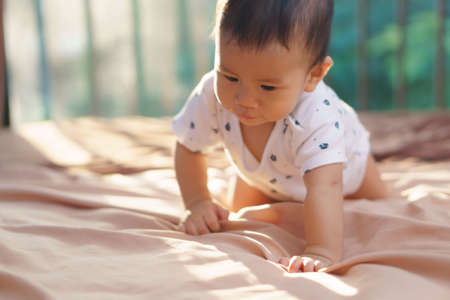 9 months Asian baby playing on the bed