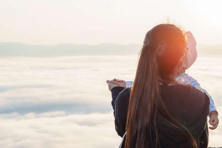 Asian Mother holding her baby to see the fog over mountainの写真素材