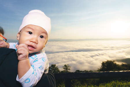 Asian Mother holding her baby to see the fog over mountainの写真素材