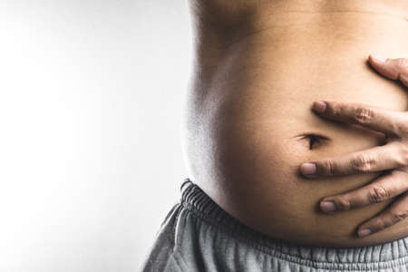 Man touching his fat belly on white backgroundの写真素材