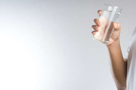 Hand holding a glass of water on white backgroundの写真素材
