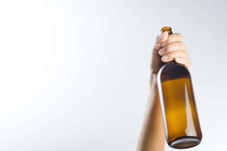 Hand holding a beer bottle without label isolated on white backgroundの写真素材