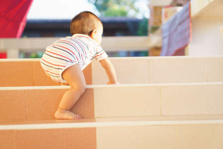 10 months adorable Asian baby development , climbing up stairs at homeの写真素材