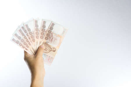 Hand holding Thai baht notes on white backgroundの写真素材
