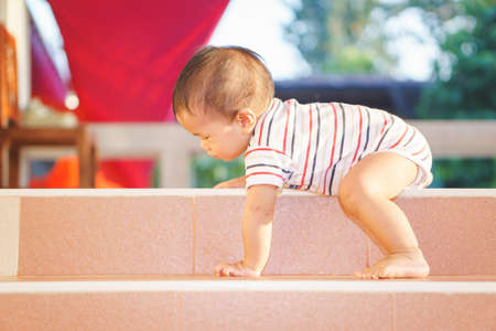 10 months adorable Asian baby development , climbing up stairs at homeの写真素材