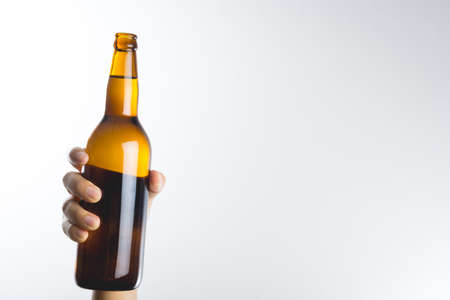 Hand holding a beer bottle without label isolated on white background
