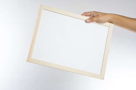 Hand holding blank wooden frame on white backgroundの写真素材
