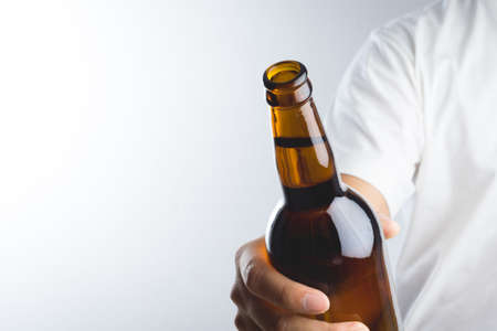 Hand holding a beer bottle without label isolated on white backgroundの写真素材