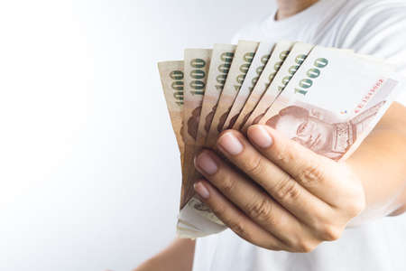 Hand holding Thai baht notes on white background