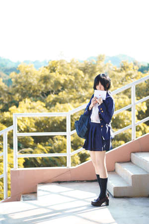 Charming Asian girl in student uniform holding love letter in her handの写真素材