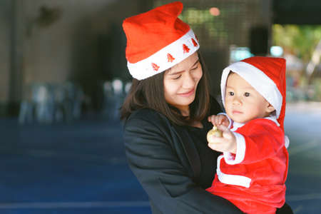 Asian mother holding 11 months old baby in santa suit