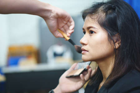 Makeup artist applies eyebrow on Asian woman faceの写真素材