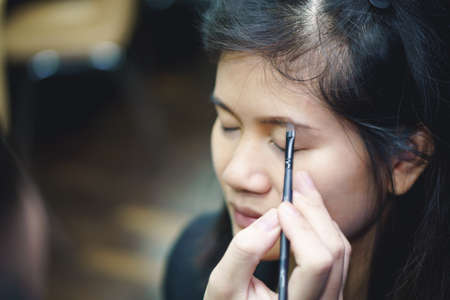 Makeup artist applies eyebrow on Asian woman faceの写真素材