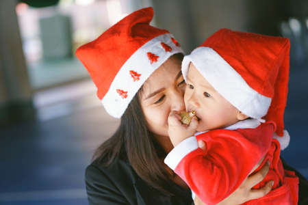 Asian mother holding 11 months old baby in santa suitの写真素材