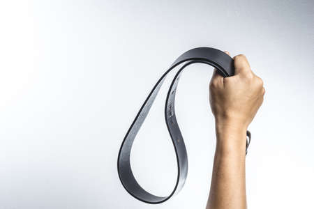 Hand holding leather belt for punishment on white background ,family violence  concept