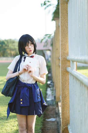 Charming Asian girl in student uniform holding love letter in her handの写真素材