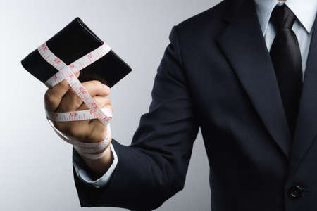 Business man with wallet wrapped by measuring tape on white backgroundの写真素材