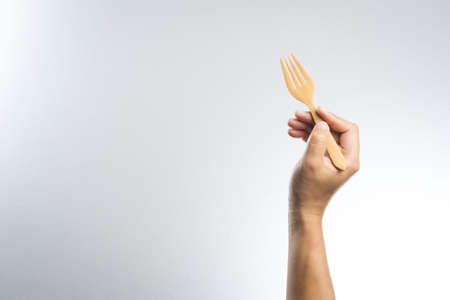 Man hand holding a wooden fork on white backgroundの写真素材