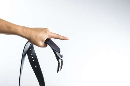 Hand holding leather belt for punishment on white background ,family violence  conceptの写真素材