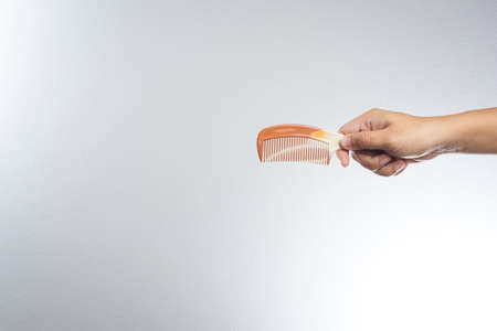 hand holding rubber comb on white backgroundの写真素材