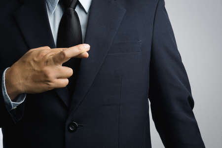 Business man with lie hand sign on white backgroundの写真素材