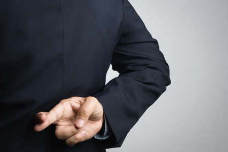 Business man with lie hand sign on white backgroundの写真素材