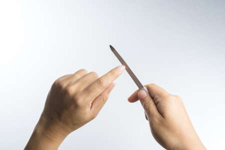 Hand with nail file for polishing fingernails on white backgroundの写真素材
