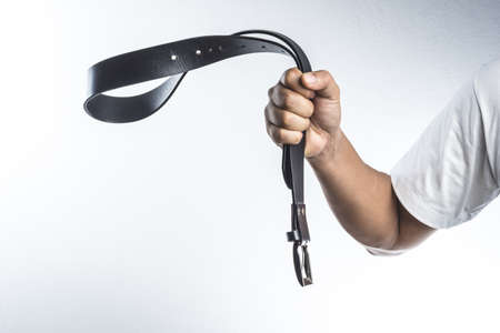 Hand holding leather belt for punishment on white background ,family violence  conceptの写真素材