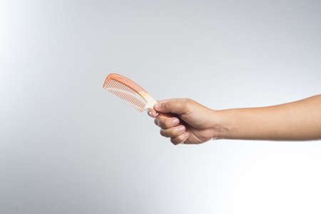 hand holding rubber comb on white background