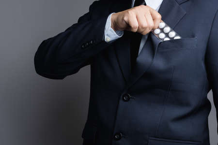 Business man hand holding white medicine pills in blister pack on white backgroundの写真素材