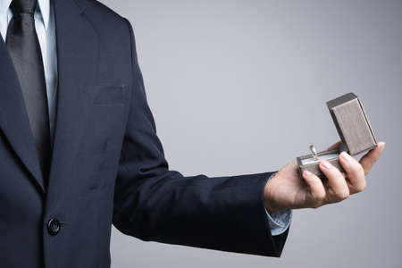 Business man hand holding box with ring on white background