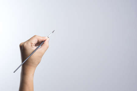 Hand holding a brush on white backgroundの写真素材
