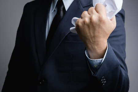 Business man hand  crunching a piece of white paper in anger on white backgroundの写真素材
