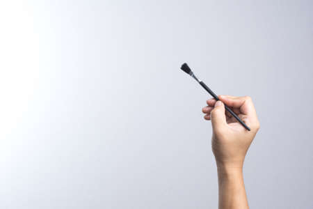 Hand holding a brush on white backgroundの写真素材