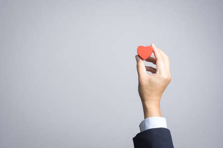 Business man hand with wooden red heart object on white backgroundの写真素材