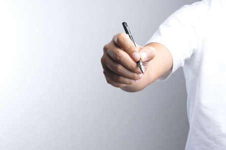 Hand holding a pen for signing or writing on white backgroundの写真素材