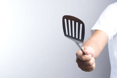 Hand holding stainless spade of frying pan on white backgroundの写真素材
