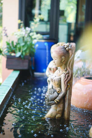 Common fountain sculpture of the Thai ancient woman in the pondの写真素材