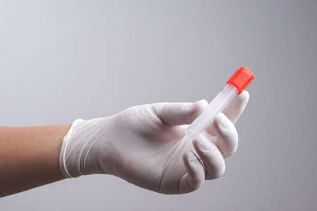 Hand with latex glove holding empty test tube on white background