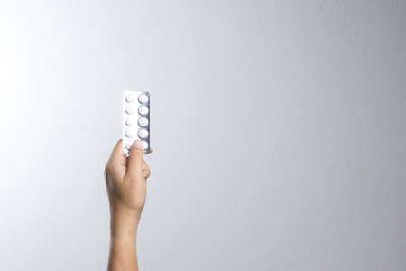 A man hand holding white medicine pills in blister pack on white backgroundの写真素材
