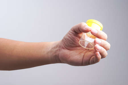 Hand holding empty urine plastic container with masturbation gesture on white backgroundの写真素材