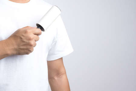 Hand with adhesive lint roller on white backgroundの写真素材