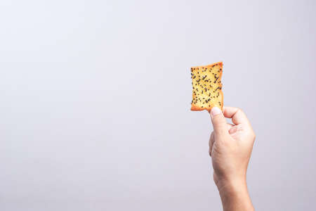 Hand holding butter rusk bread loaf with black sesame on white backgroundの写真素材