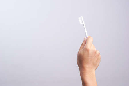 Hand holding old toothbrush need to change for new one on white backgroundの写真素材