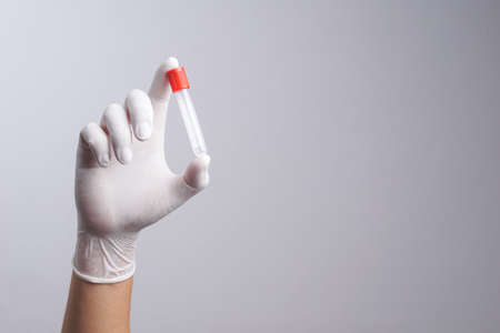Hand with latex glove holding empty test tube on white background