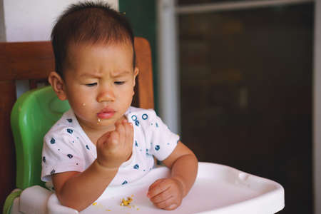 1 year old Asian baby eating food by himself