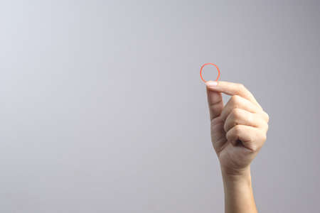 Hand holding elastic rubber band on white backgroundの写真素材
