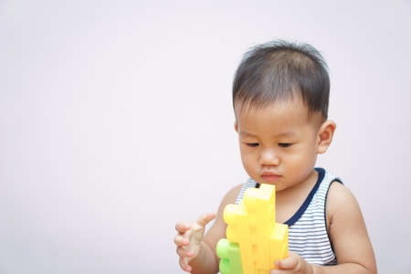 A 1 year and 4 months Asian baby playing plastic blocks for self developmentの写真素材
