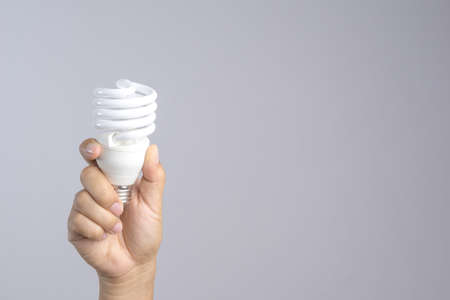 Hand holding compact fluorescent light bulb on white backgroundの写真素材