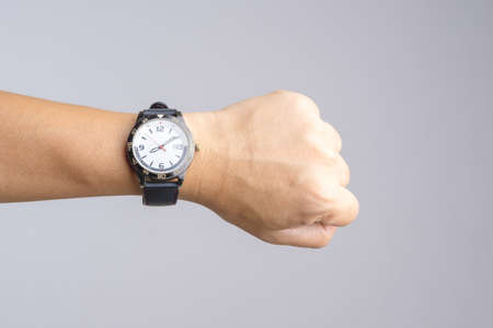 Hand with old and rusty wrist watch showing time over eight o'clock for being late on white backgroundの写真素材
